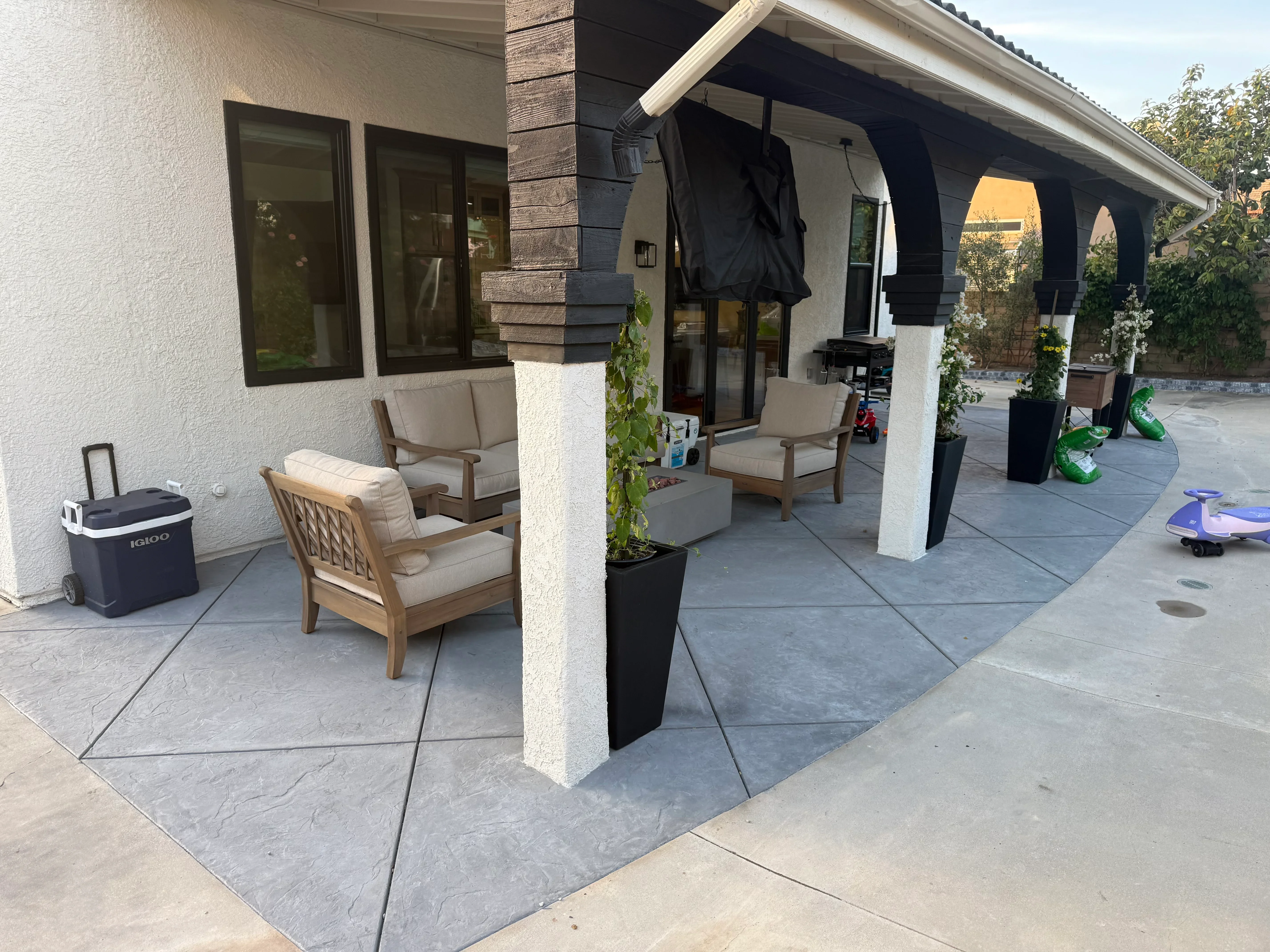 Stamped slate-pattern concrete patio with white pergola and support columns