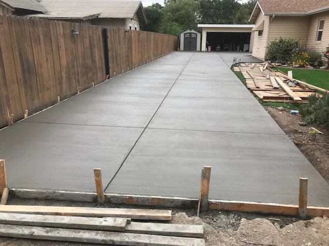Freshly poured concrete driveway with control joints and wooden forms, residential setting