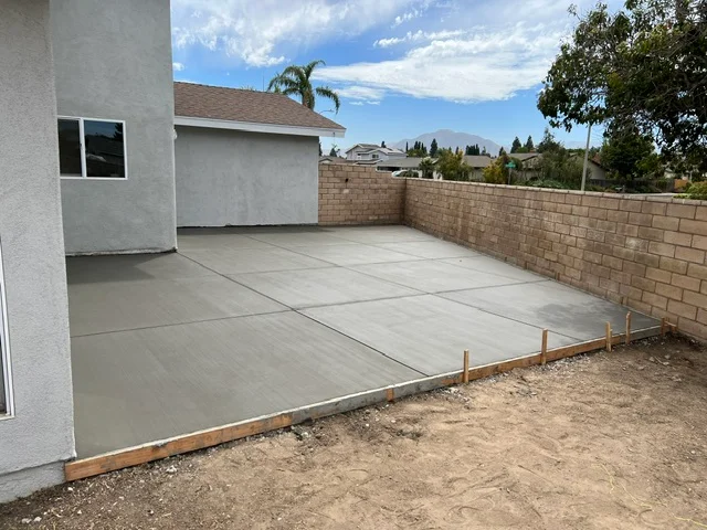Finished concrete patio with control joints and brick retaining wall