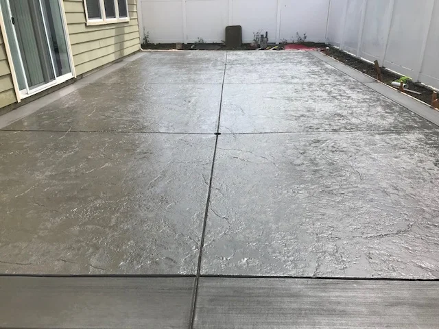 Freshly poured concrete patio with control joints and smooth troweled finish