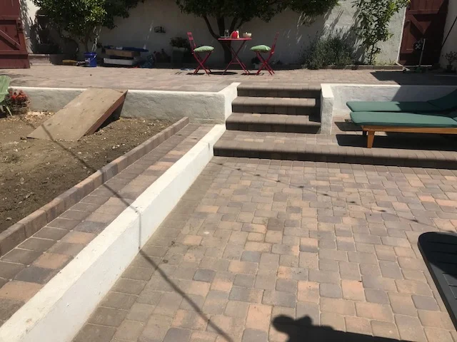 Clay brick paver patio with concrete steps and white retaining wall edging
