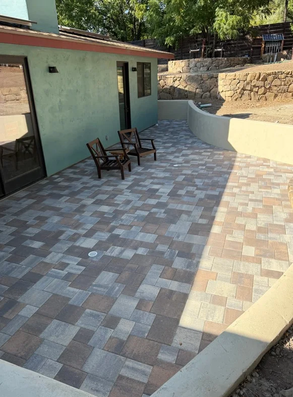 Geometric patterned concrete paver patio with curved border wall and clay brick transition