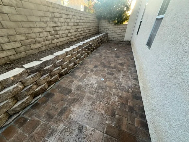 Herringbone paver patio with stacked stone retaining wall in narrow side yard