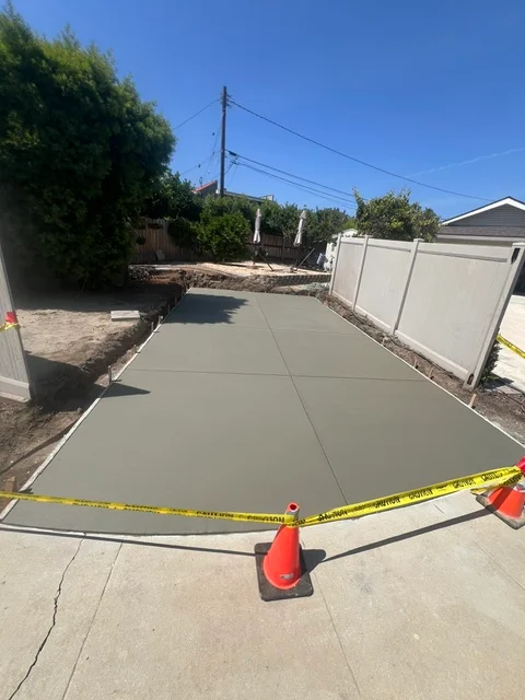 Newly poured concrete driveway with control joints and yellow safety tape during curing