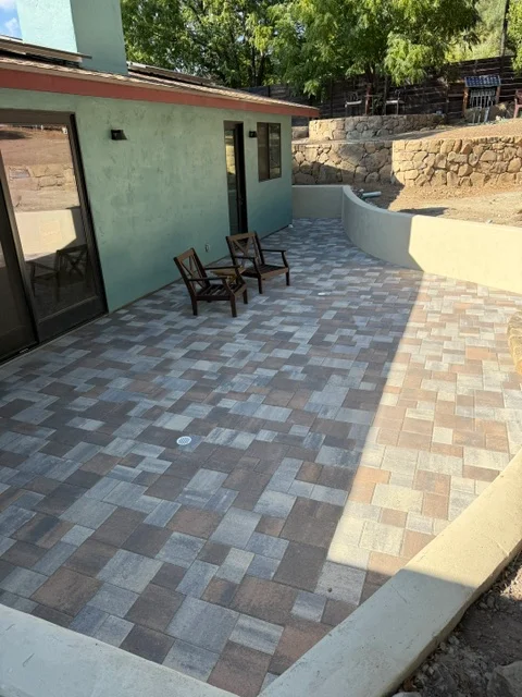Geometric patterned paver patio with earth-tone pavers and concrete border