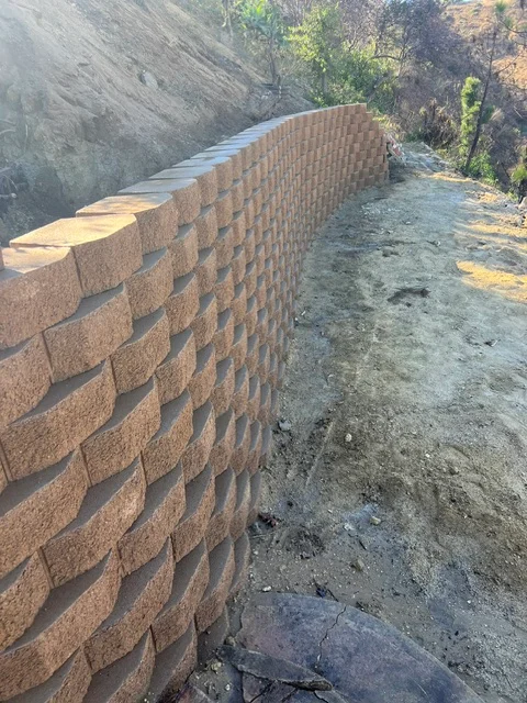 Curved stone retaining wall with running bond pattern on hillside slope