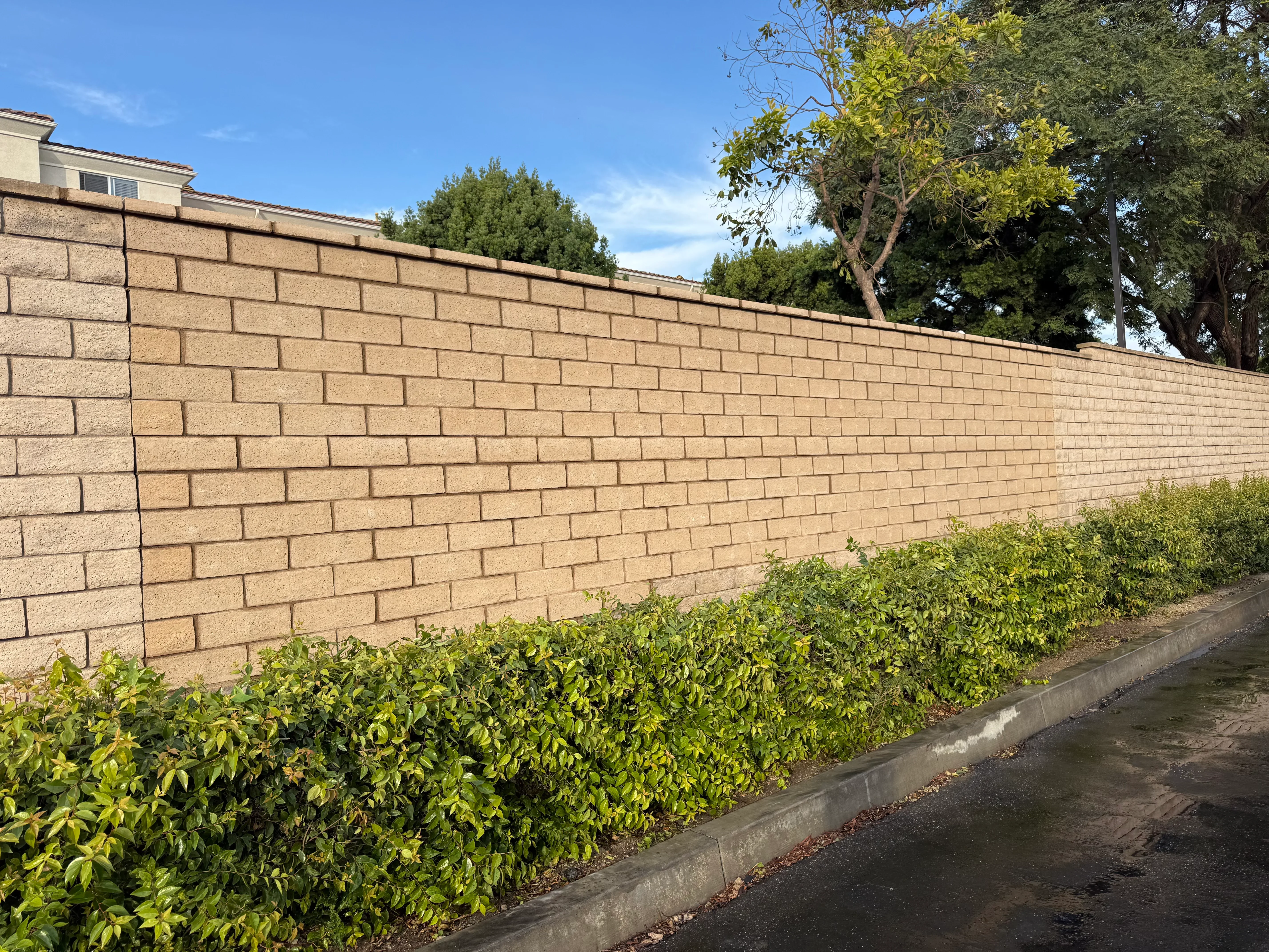 Tan brick veneer concrete retaining wall with running bond pattern and concrete base