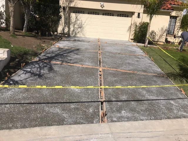 Concrete driveway demolition with marked sections and removal in progress