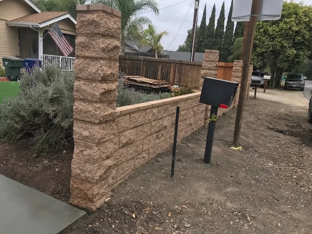 Clay brick retaining wall with metal rail installed along residential driveway