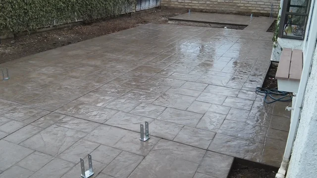 Newly poured concrete patio with decorative scoring pattern and metal posts