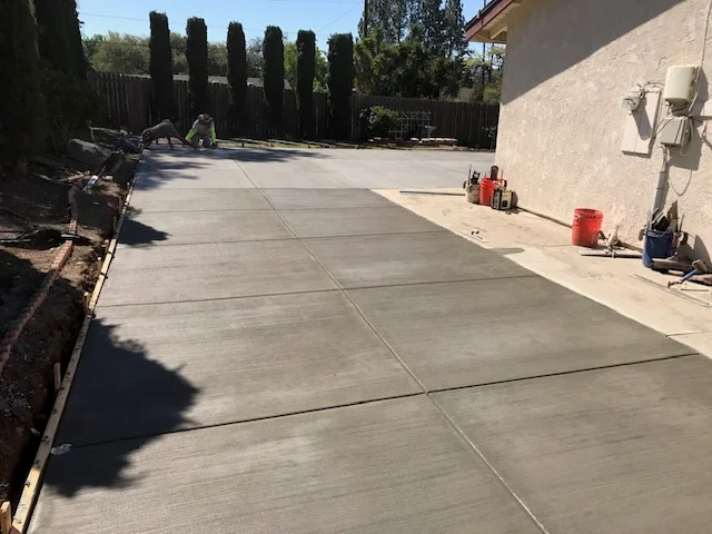 Freshly poured concrete patio with control joints and smooth gray finish