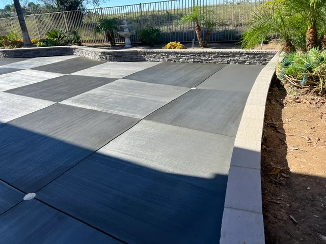 Gray concrete patio with scored pattern, concrete border, and integrated landscape features