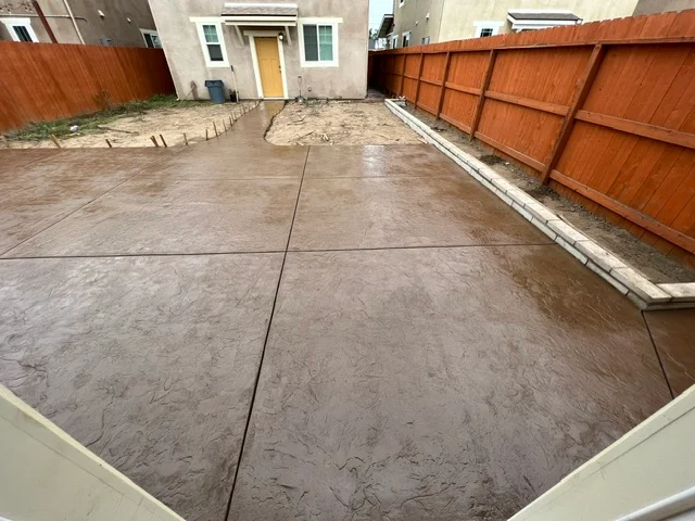 Newly poured concrete patio with control joints and finished trowel surface in residential backyard