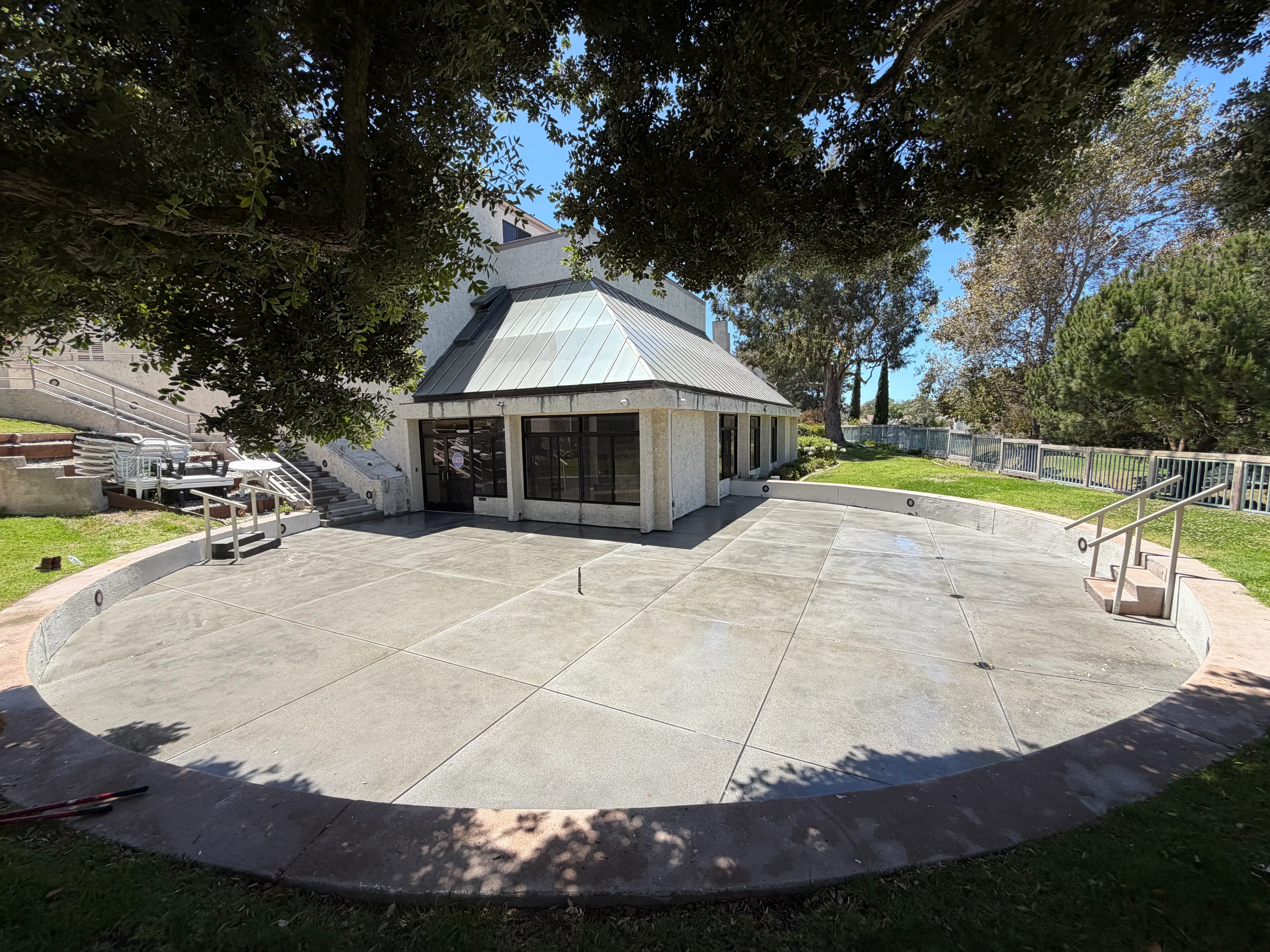 Curved concrete patio and walkway with control joints adjacent to modern pavilion building