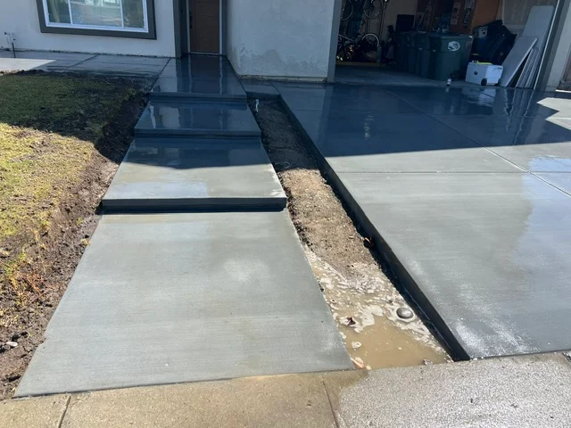 Concrete walkway with black edging and finished patio adjacent to residential home