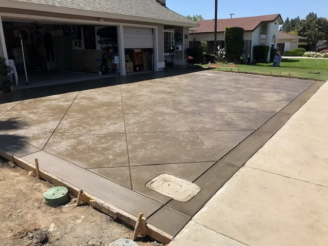 Newly poured concrete driveway and patio with decorative scoring patterns and border detail