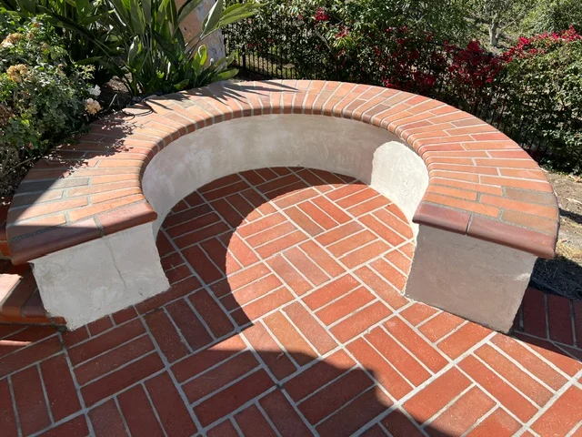 Curved brick fire pit with herringbone pattern and concrete seating bench