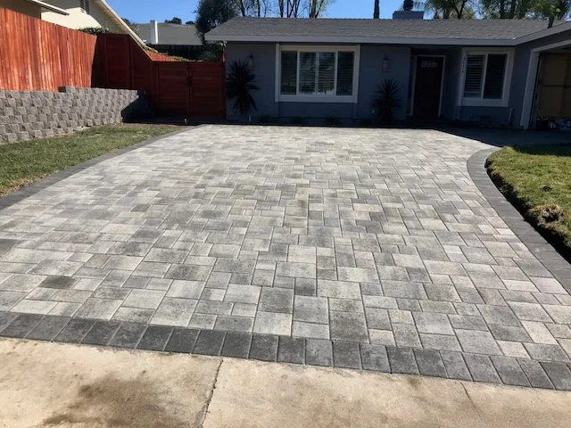 Newly installed permeable concrete paver driveway with herringbone pattern and curved edges