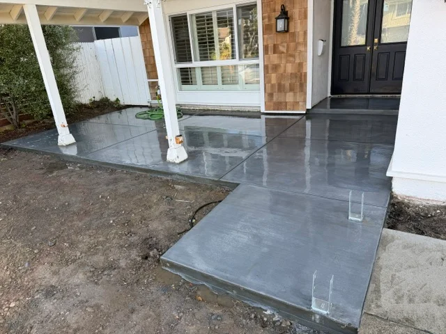 Dark gray concrete patio and entryway with stepped platform and white support columns