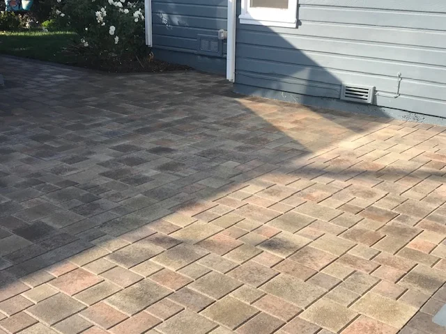 Herringbone patterned paver driveway with charcoal and tan concrete pavers installed next to garage
