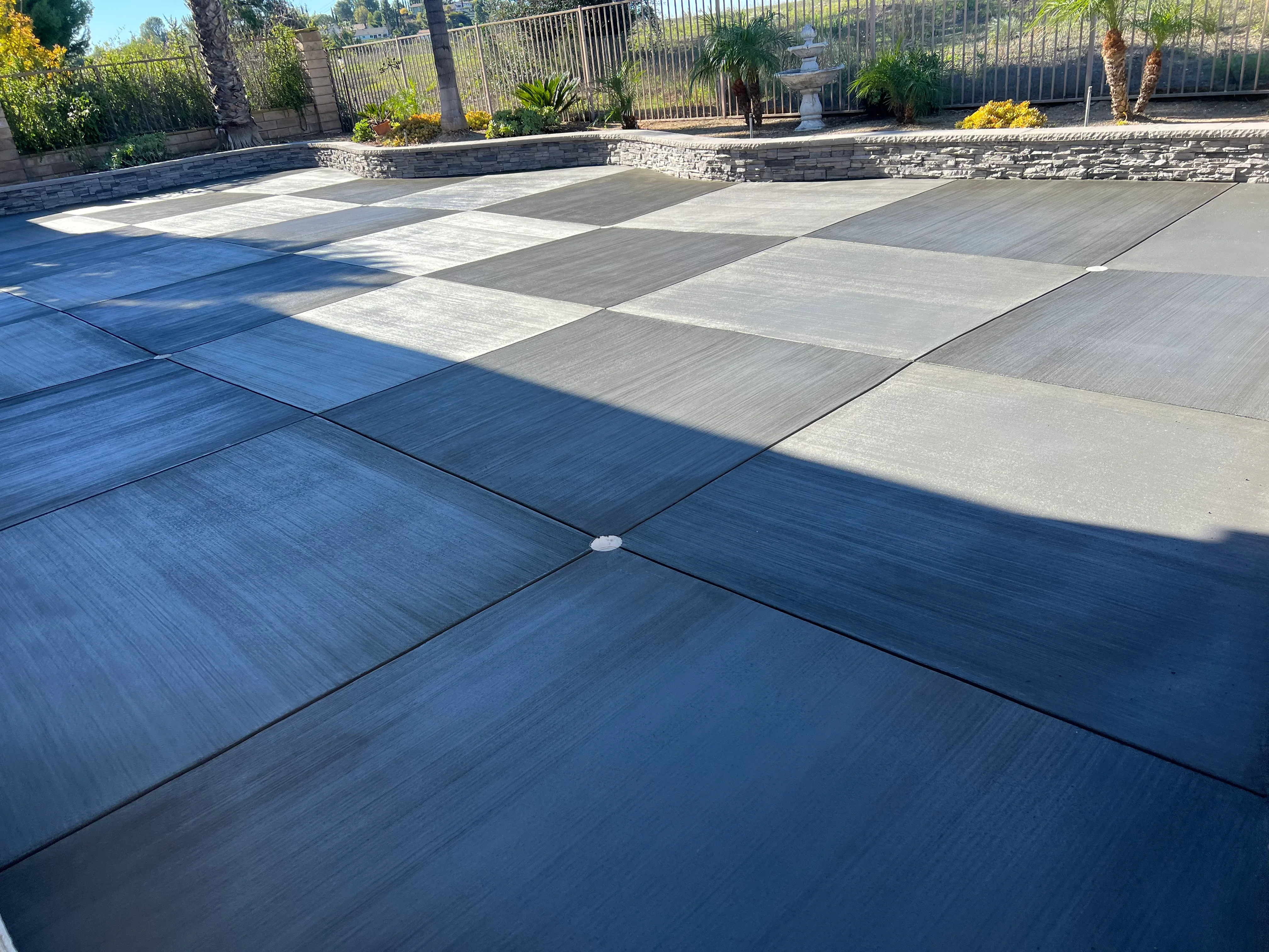 Large concrete patio with geometric pattern, mixed gray finishes, and decorative scoring