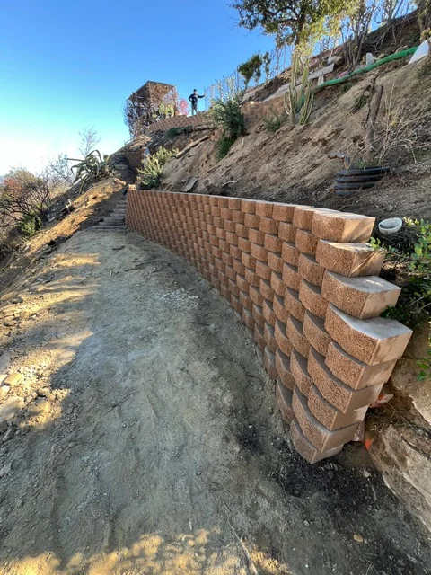 Stacked brick retaining wall with stepped tiers on hillside slope