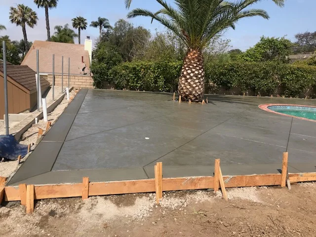 Gray concrete patio with wooden forms and finished edges during installation