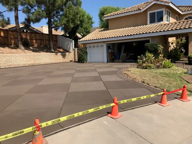 Fresh concrete driveway with control joints and caution tape during curing process