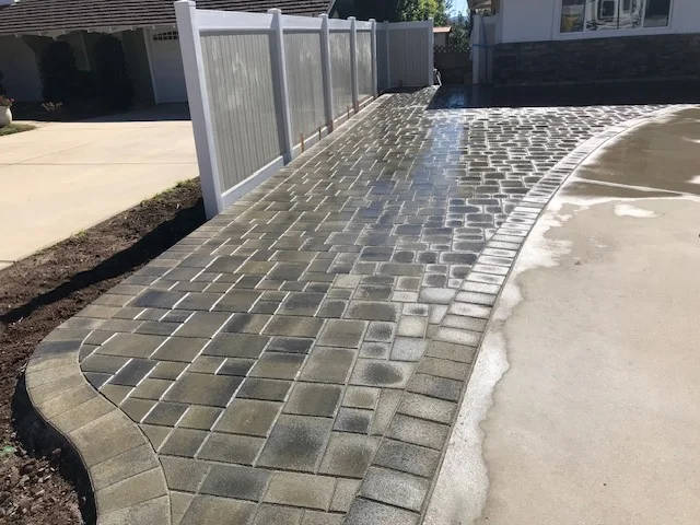 Herringbone patterned permeable pavers with curved concrete border and edging