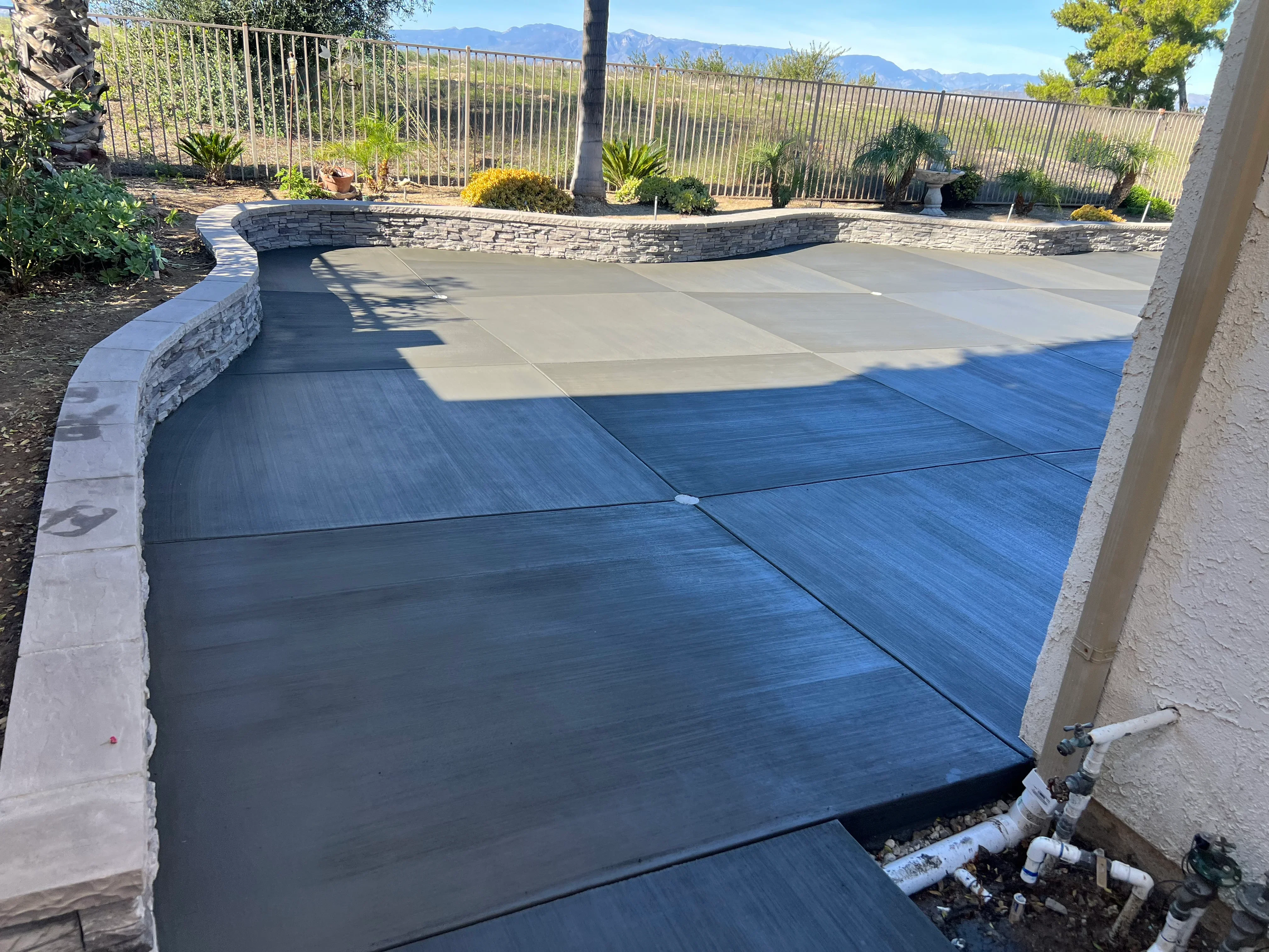 Two-tone stained concrete patio with curved stacked stone seating walls and control joints