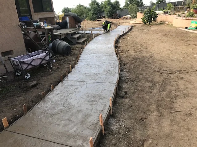 Newly poured concrete walkway with wooden forms and troweled finish