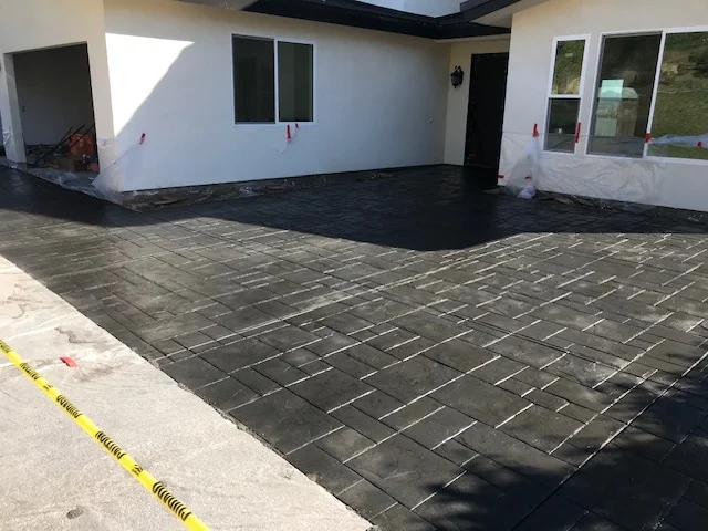 Stamped concrete patio with herringbone brick pattern in charcoal gray finish