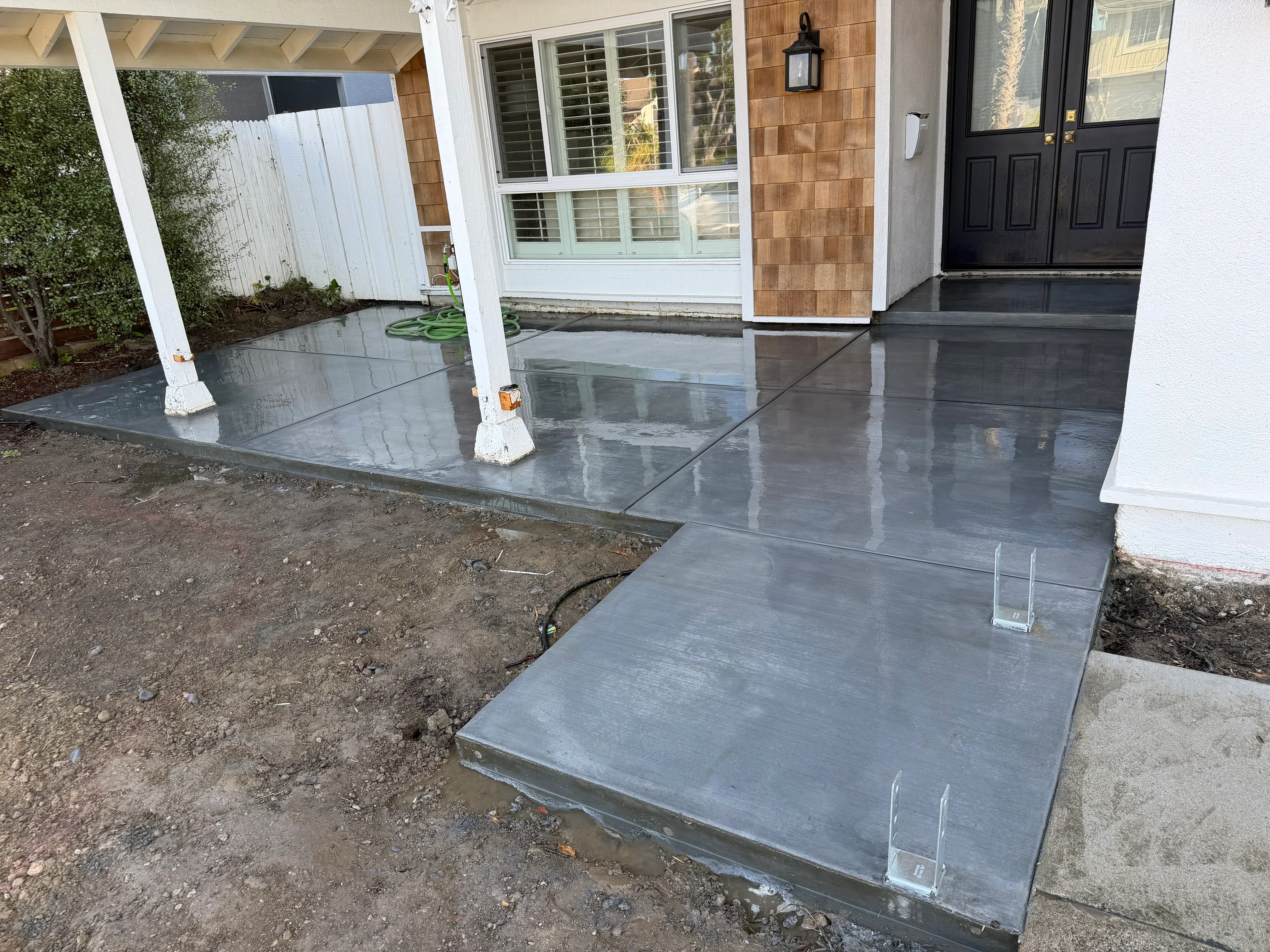 Polished dark gray concrete patio with control joints and white support posts