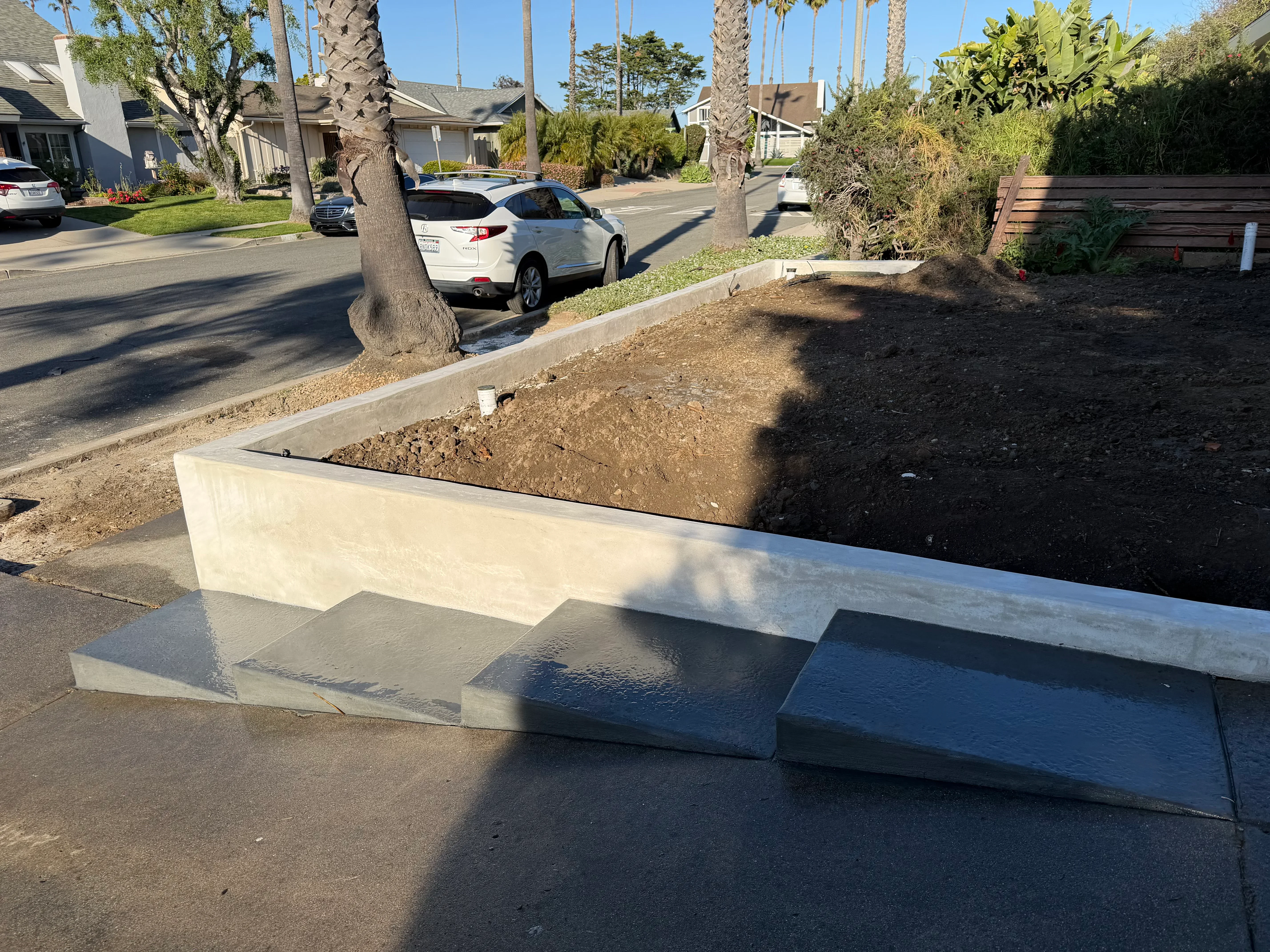 Concrete retaining wall with stepped cap and finished concrete surface, residential street setting